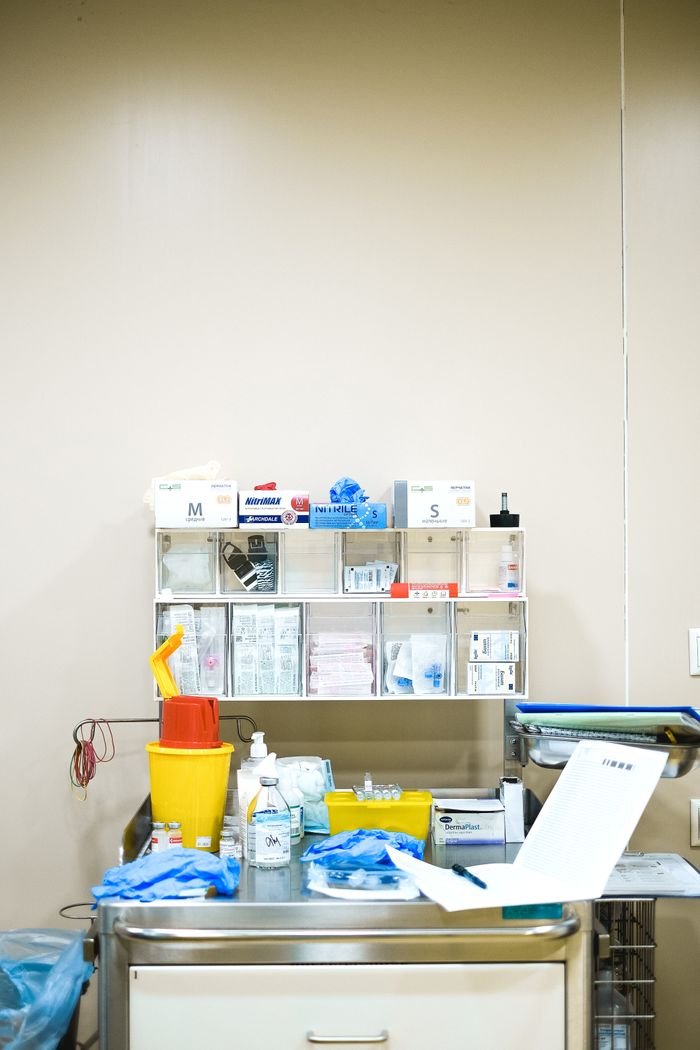 services-02 Neatly arranged medical supplies on a shelf in a hospital setting, featuring gloves, containers, and paperwork.